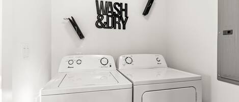 A laundry room with two white washing machines and a wall-mounted sign that reads 'WASH & DRY.'
