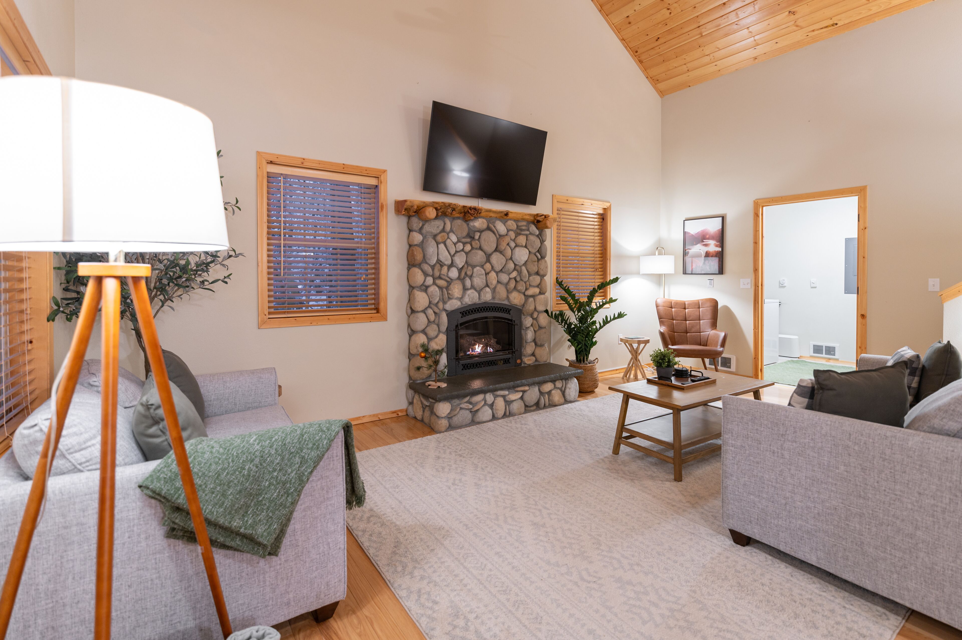 Una sala de estar acogedora con chimenea de piedra, un televisor montado en la pared y un espacio de estar cómodo con sofás y una mesa de centro.