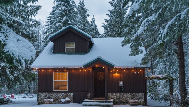 Une cabane rustique avec des fondations en pierre, un revêtement extérieur en bois et un toit enneigé.