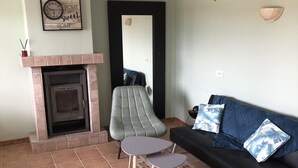Ein Wohnzimmer mit Kamin, einer Couch, einem Sessel und einem kleinen Tisch.