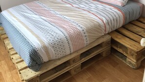 Ein Bett mit gestreifter Decke und Kissen auf Holzbalken.