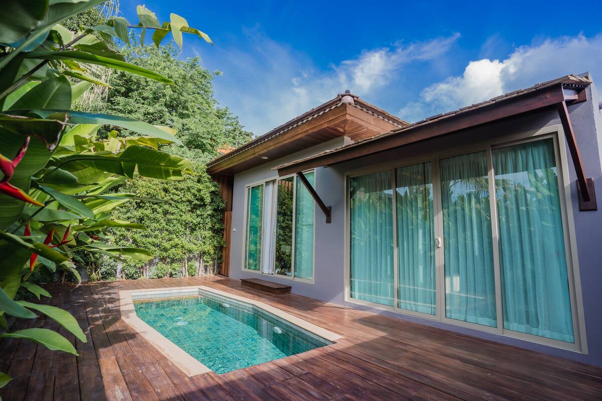 Ett modernt hus med en swimmingpool, stora fönster och en träaltan.
