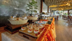 Un'impostazione per buffet con diversi cibi e bevande, un cesto in vimini e una pianta in vaso.