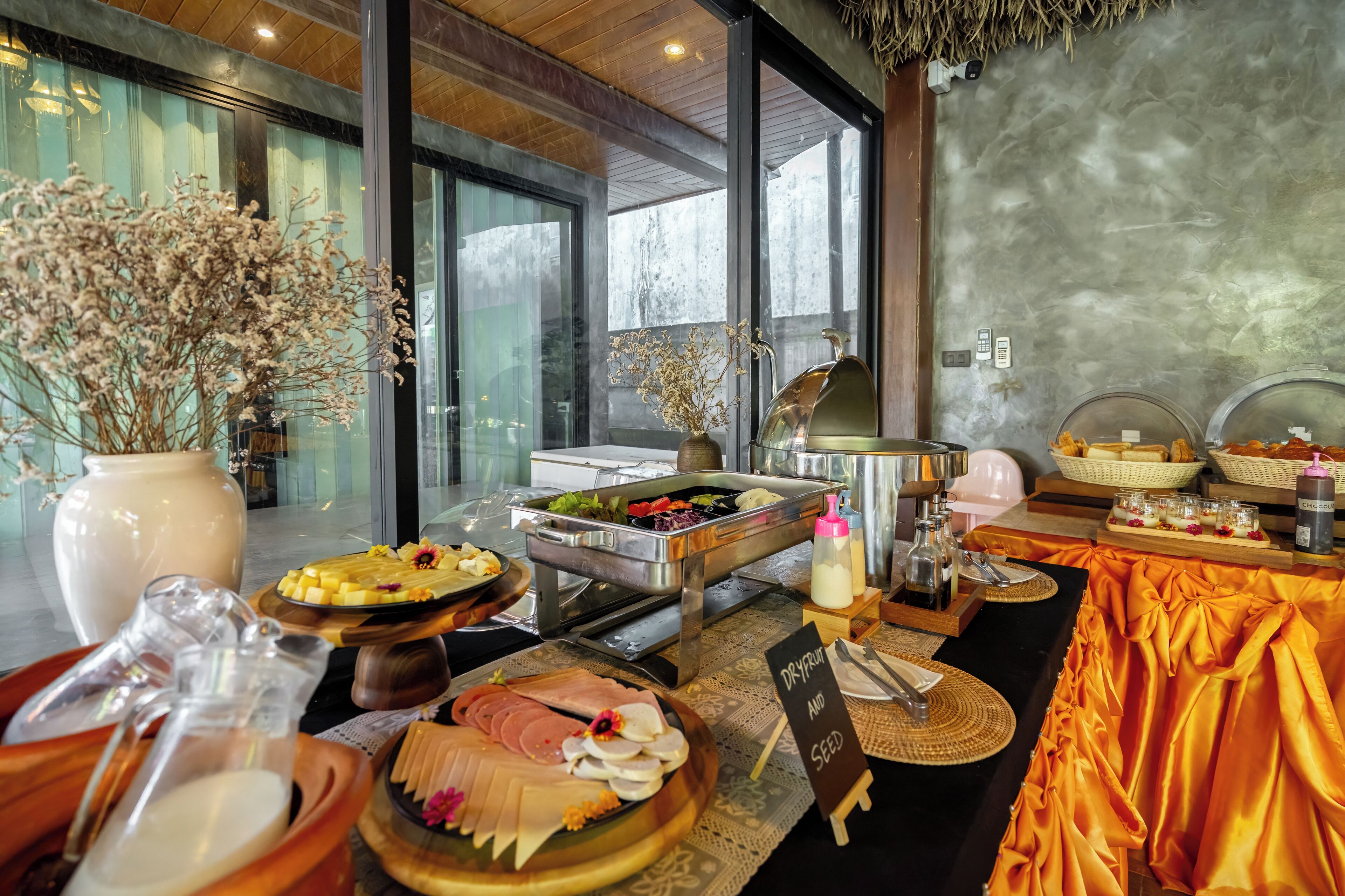 A buffet with various food items, a large vase with dried flowers, and a sign indicating 'Dry Fruit and Seed'.
