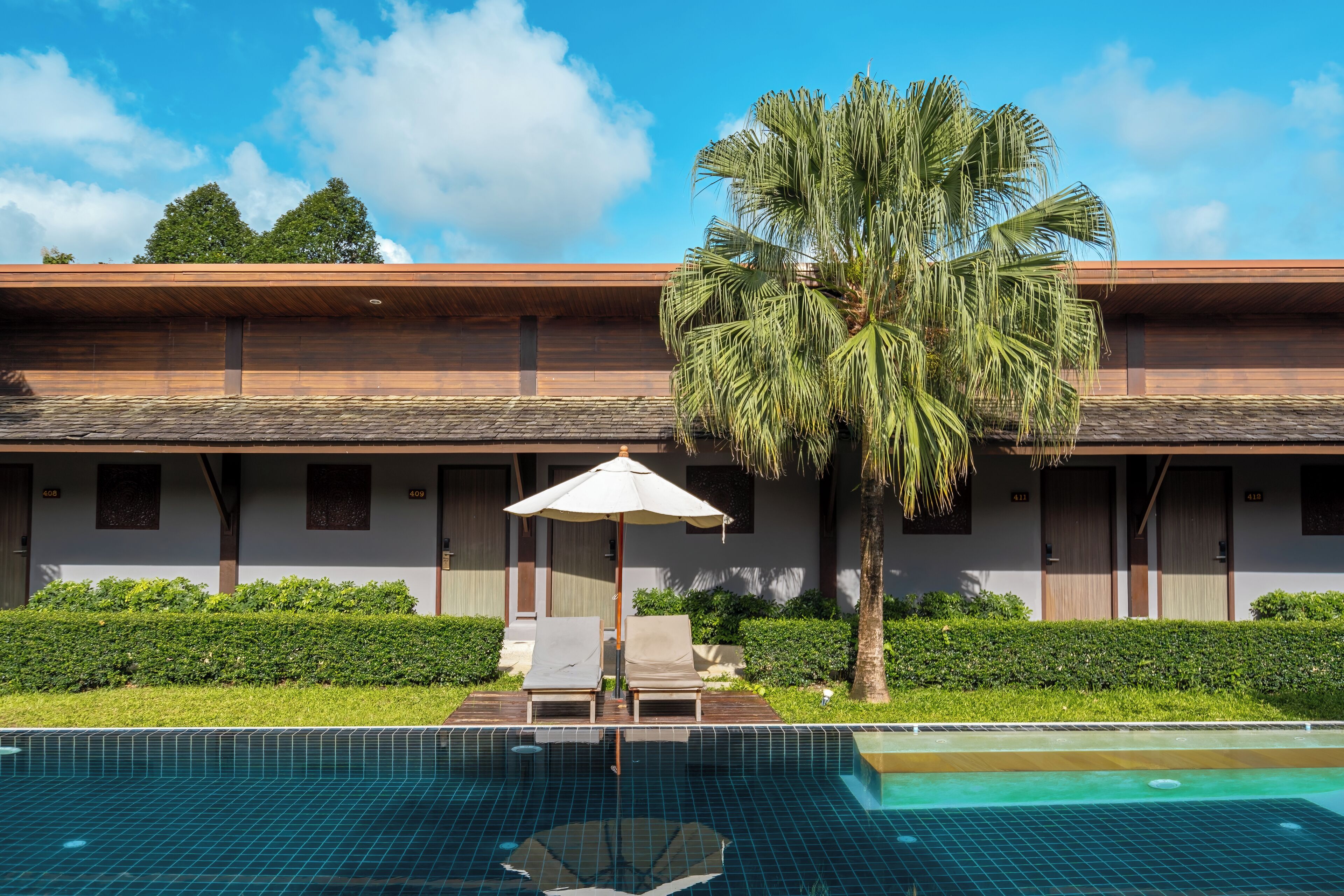 A hotel with a swimming pool, palm trees, and a modern architectural design.