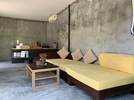 Una habitación moderna con una recepción, un sofá, una pequeña mesa y una pared de concreto.