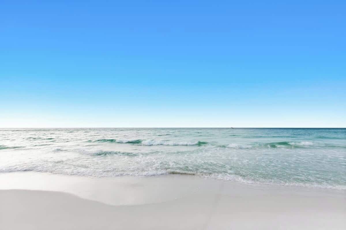 Una playa con cielos despejados y olas suaves.