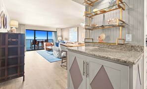A modern kitchen with granite countertops, a dining area with a view, and a balcony with a view.