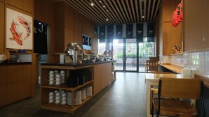 A modern cafe interior with a counter, seating area, and a view of the outdoors. - Hotel Osaka Pik2 (Kosambi)