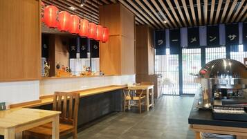 A restaurant interior with wooden furniture, a coffee machine, and red lanterns.