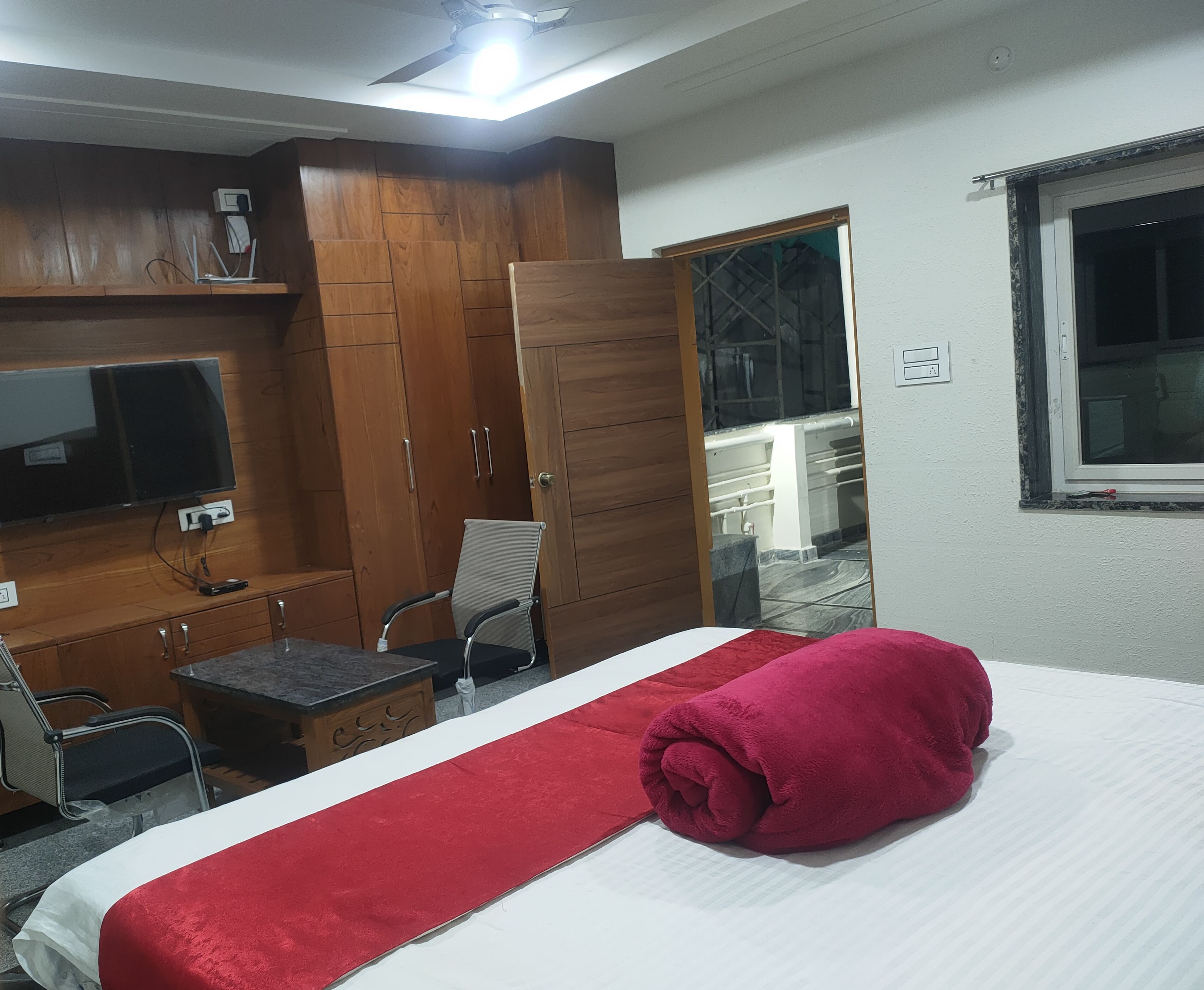 Un dormitorio con cama, televisión, armario de madera y una silla.