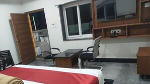 Ett hotellrum med en säng, ett skrivbord, en stol, en garderob i trä och ett fönster.