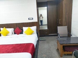A hotel room with a bed, a desk, and a wardrobe. - Hotel New Maruthi Inn (Hyderabad)