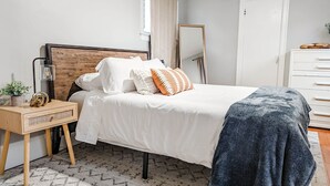 Ein Schlafzimmer mit einem Bett, einem Nachttisch, einem Spiegel und einer Kommode.