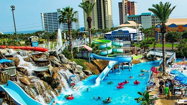 A water park with multiple slides and water features, surrounded by palm trees and buildings. - Waterview Villa~Steps to Beach~Pool~King Bed (Destin)