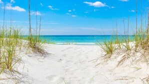 A sandy beach path leading to the ocean with clear blue water and a bright sky. - Waterview Villa~Steps to Beach~Pool~King Bed (Destin)