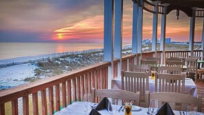 A restaurant with tables set for dining, overlooking a beach and ocean during sunset. - Waterview Villa~Steps to Beach~Pool~King Bed (Destin)