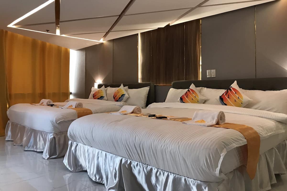 Une chambre d’hôtel moderne dotée de deux lits «queen size», d’une grande fenêtre et d’un design contemporain au niveau du plafond.