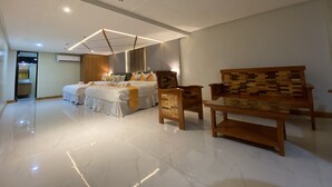 Ett rymligt hotellrum med en stor säng, en träbänk och en modern takdesign.