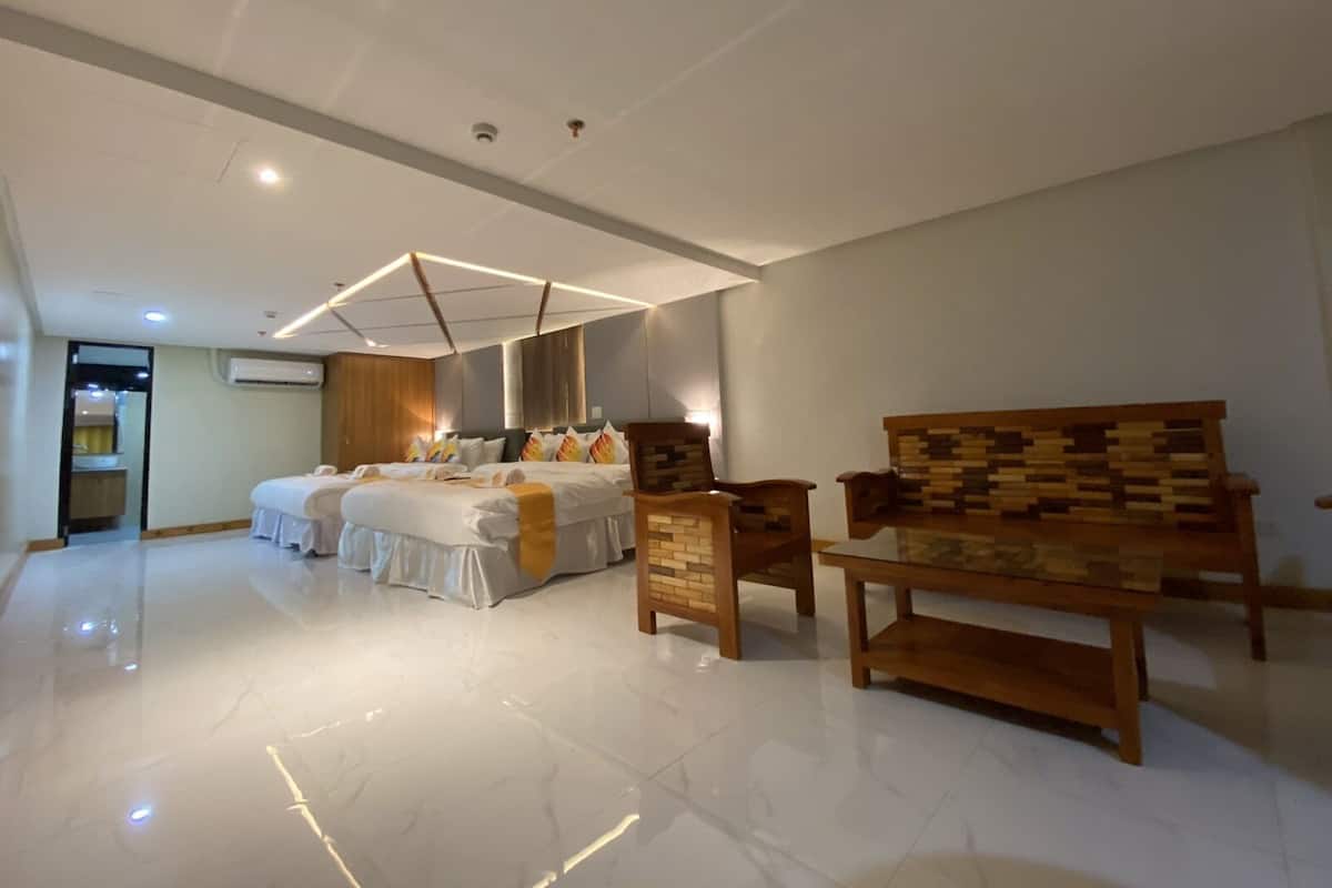 Une chambre d’hôtel spacieuse, dotée d’un grand lit, d’un banc en bois et d’un design moderne au niveau du plafond.