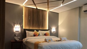 Ett modernt hotellrum med en stor säng, sänglampor, en telefon och ett litet bord.