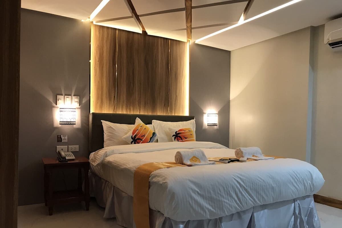 Une chambre d’hôtel moderne avec un grand lit, des lampes de chevet, un téléphone et une petite table.