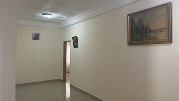 A hallway with a ceiling with decorative molding, a framed painting on the wall, and a door at the end.