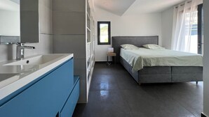 Et moderne soveværelse med en stor seng, et natbord og et vindue med gardiner.