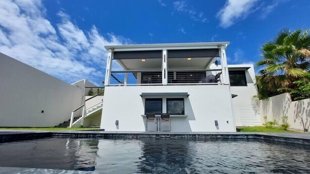 Et moderne hus med to etager og en swimmingpool foran.