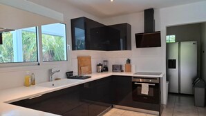 Una cocina moderna con una isla grande, electrodomésticos integrados y vistas a zonas verdes.