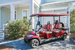 A red golf cart parked in front of a house with a porch.