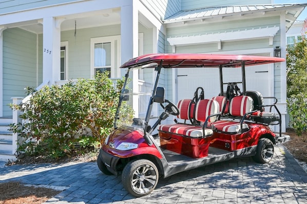 A red golf cart parked in front of a house with a porch.
