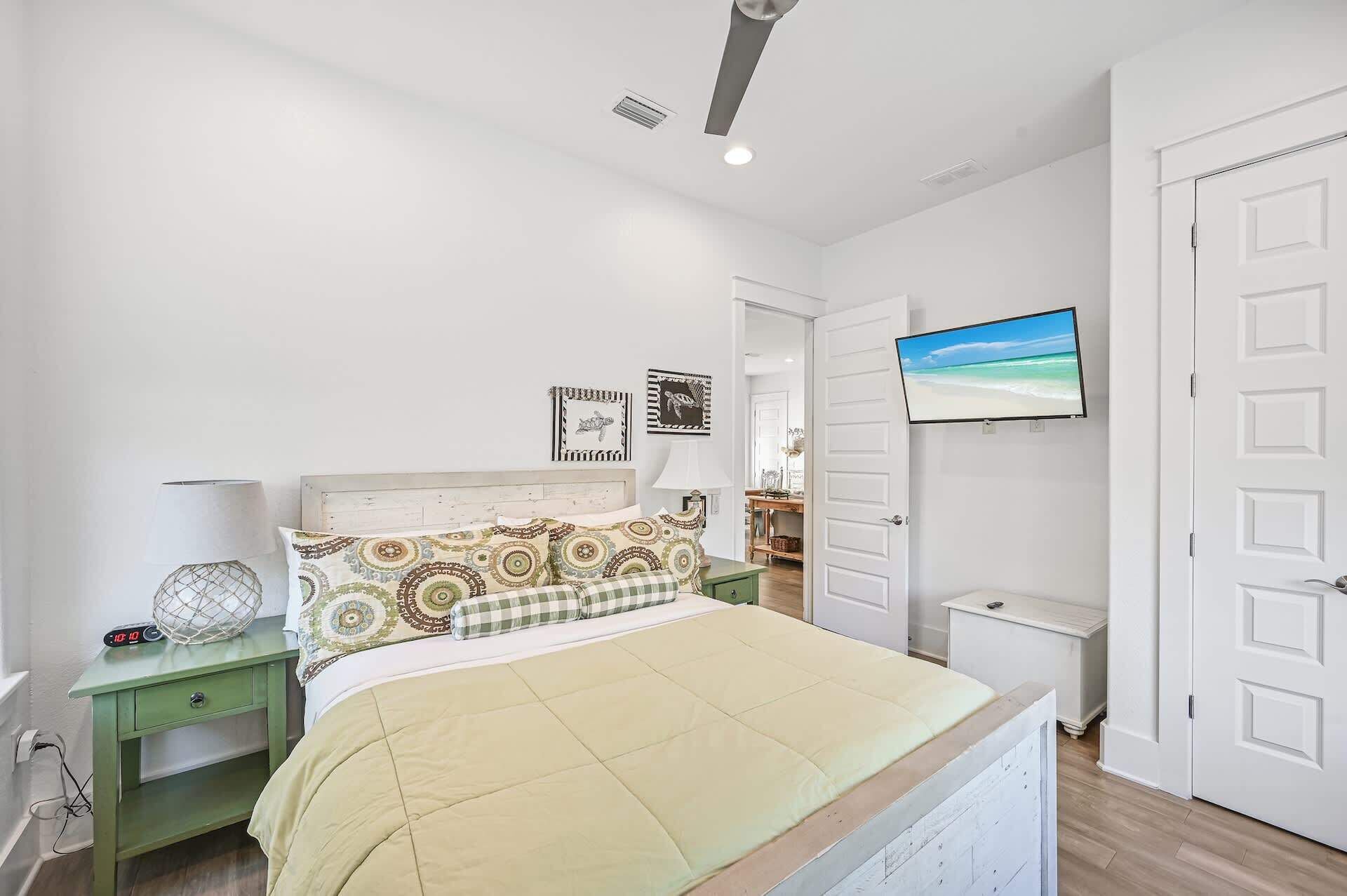 Un dormitorio con cama, mesita de noche, lámpara, televisor y puerta.