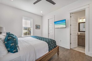 Relax in this serene bedroom with a large bed, ceiling fan, and framed picture.