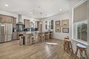 Une cuisine moderne dotée d’un îlot central, d’appareils électroménagers en acier inoxydable et de tabourets de bar en bois.