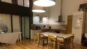 Eine moderne Küche mit Holzboden, einem Esstisch mit Stühlen und einem Kühlschrank.