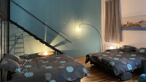 Ein Schlafzimmer mit Bett, Schreibtisch, Stuhl, einer Leiter und einem Fenster mit Vorhängen.
