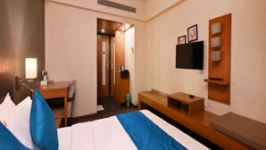 Une chambre d’hôtel avec un lit, un bureau, une chaise, une télévision et un banc.