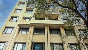 Un immeuble à plusieurs étages, doté d’une façade plane, de fenêtres rectangulaires et d’un balcon à l’étage supérieur.