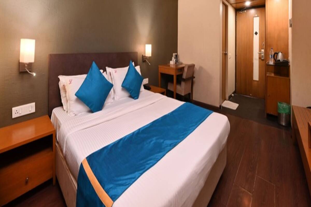 A hotel room with a bed, bedside tables, a desk, and a wardrobe.