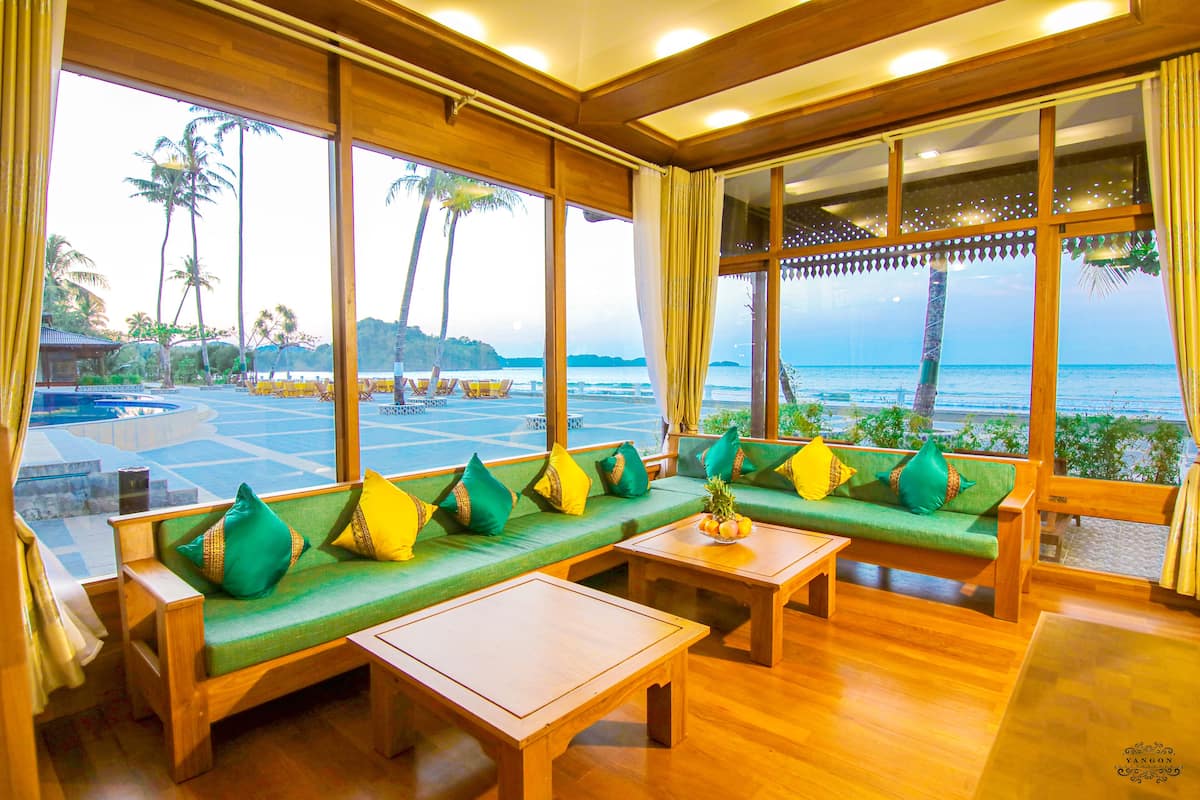 Una habitación con muebles de madera, ventanas amplias y vista a la playa.