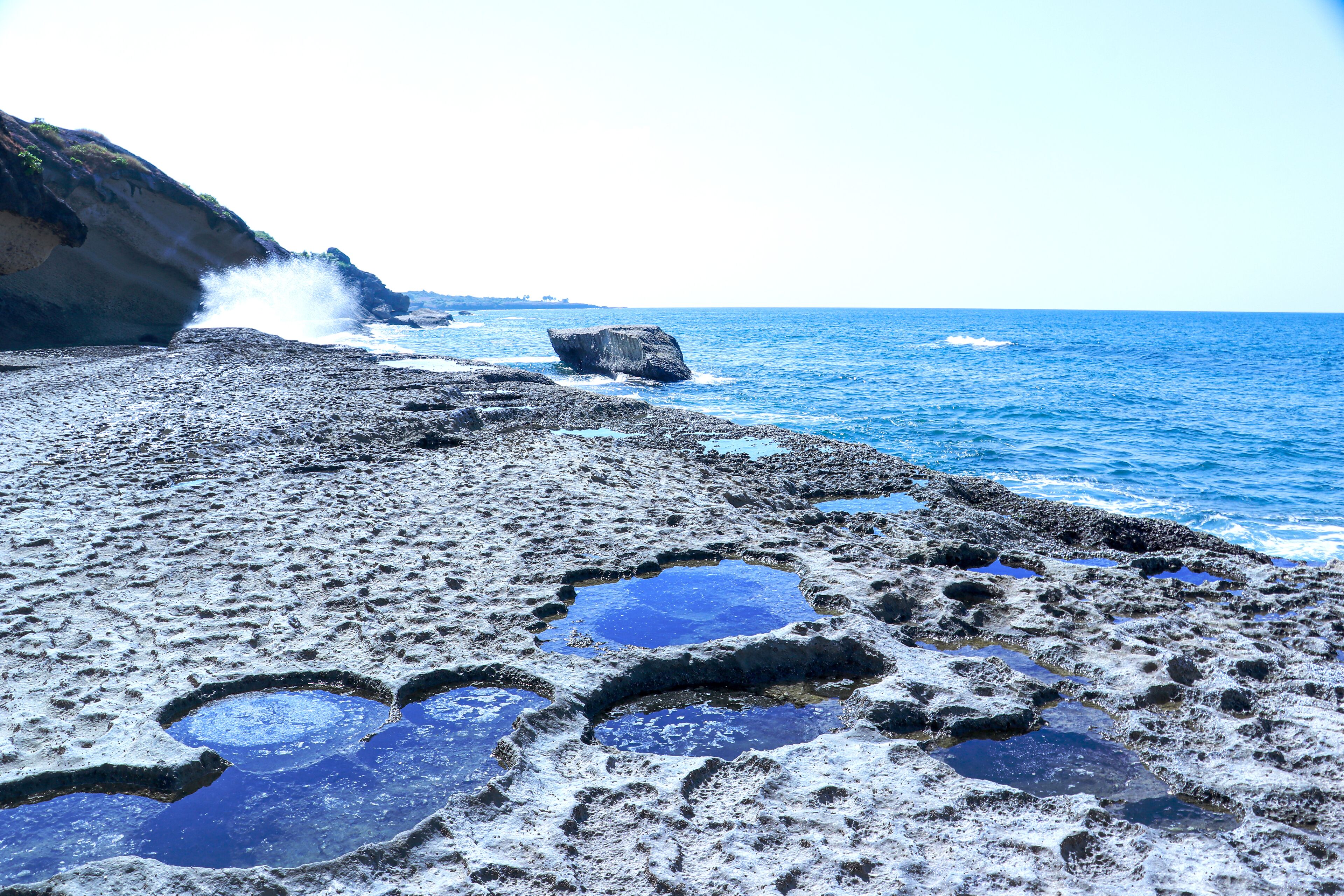 A rocky beach with clear blue water and a cliff.