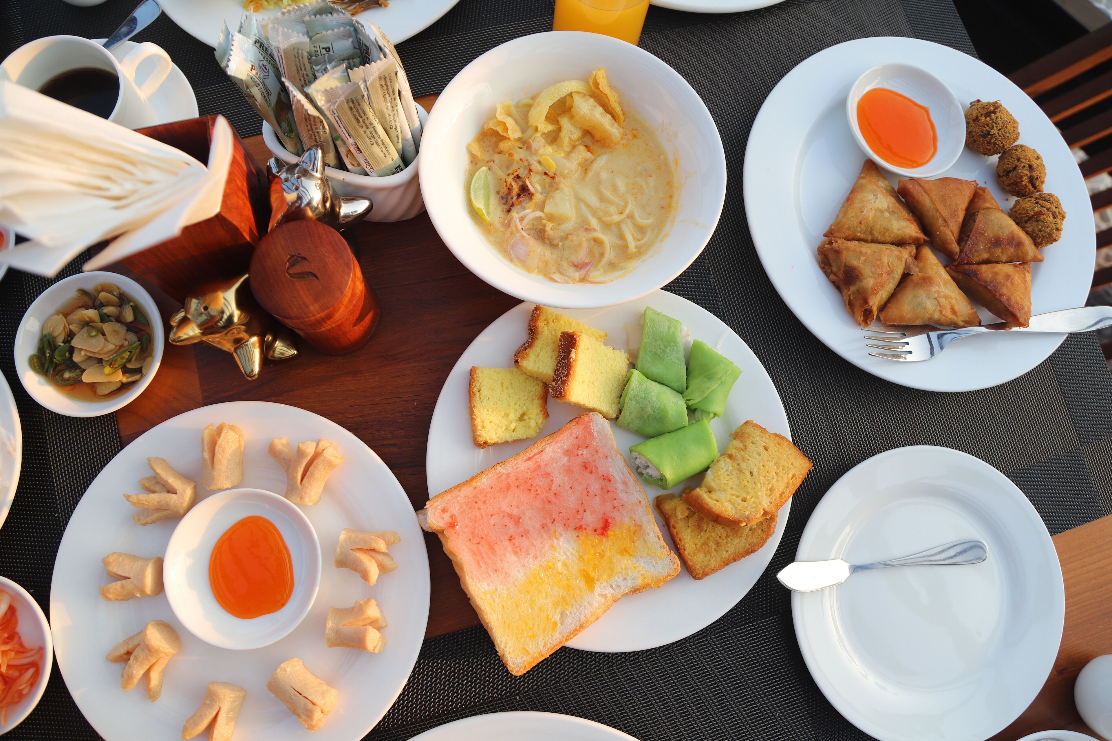A table with various dishes including a bowl of soup, bread, and a plate with fried items.
