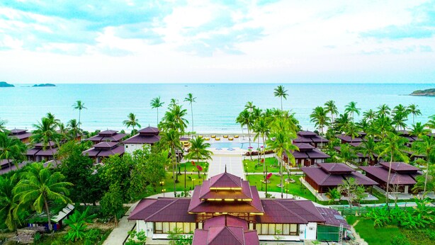Um resort com vários edifícios, piscina e vista para a praia.