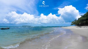 Uma praia com águas cristalinas, um barco e o logotipo do Gaw Yan Gyi Hotel & Resort.