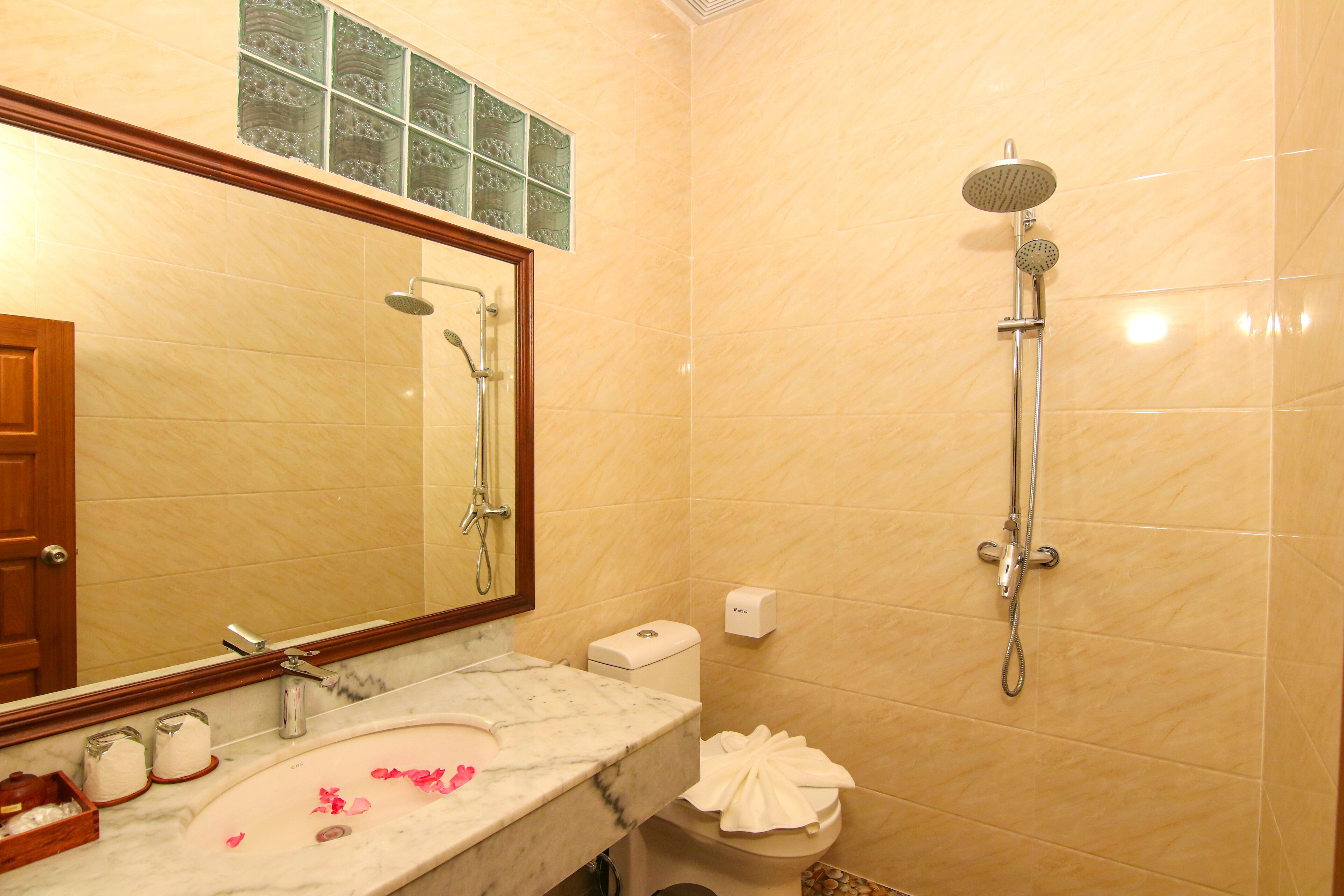 A bathroom with a marble sink, a toilet, a shower, and a mirror.