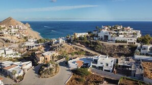 Un pueblo costero con edificios blancos, una playa y una montaña al fondo.