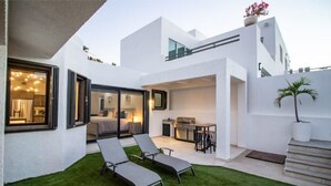 Una casa moderna con un patio, una zona de comedor y un dormitorio con un gran ventanal.