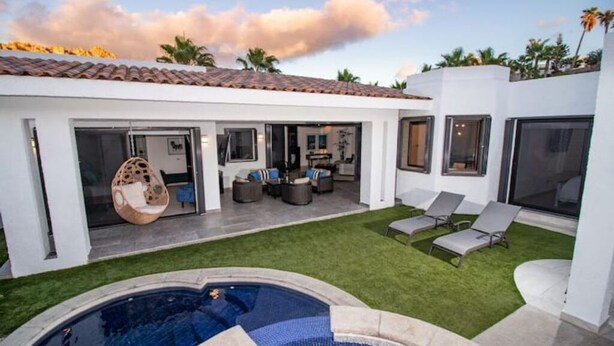 Una casa moderna con piscina, zona de estar exterior y patio.