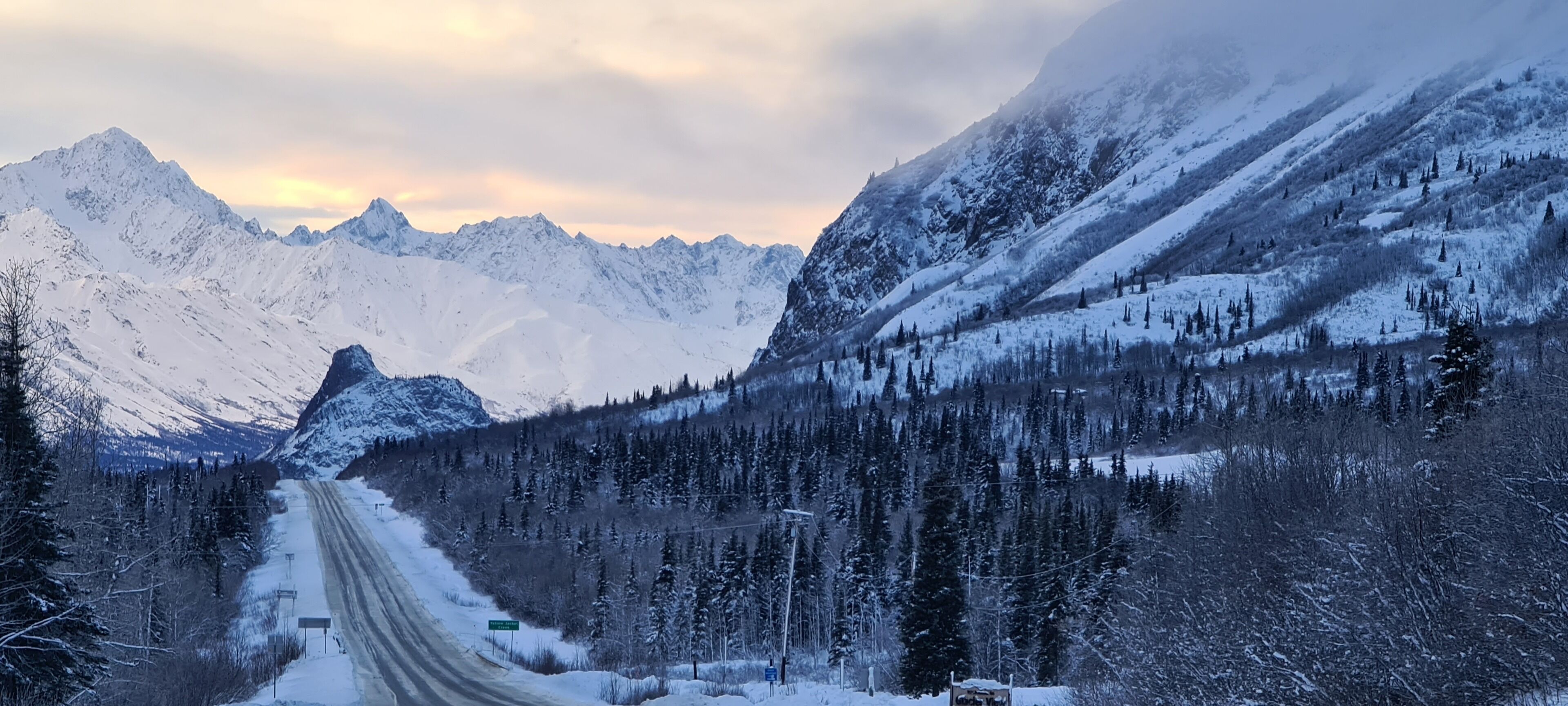 Una carretera de montaña cubierta de nieve bajo un cielo despejado.